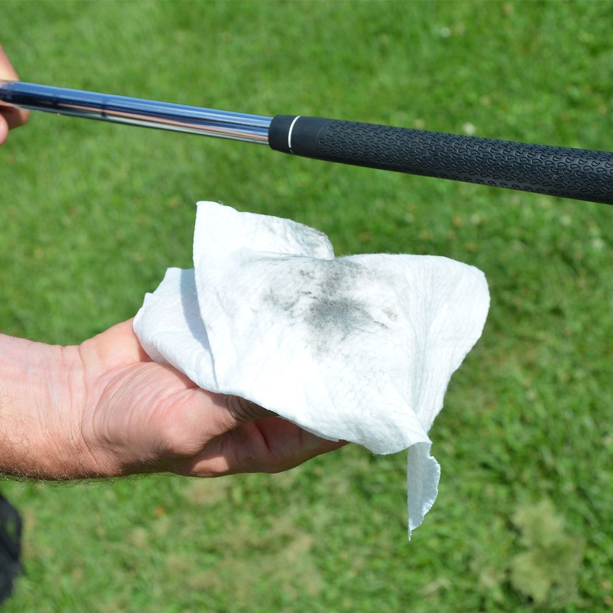 person holding a golf club in one hand in the other is residue on a Karma Grip Cleaning Wipe